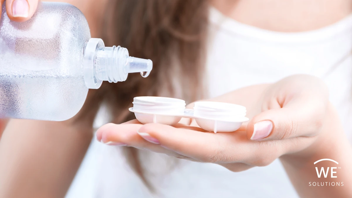 Person filling a contact lens case with multi-purpose solution during a daily contact lens care routine.